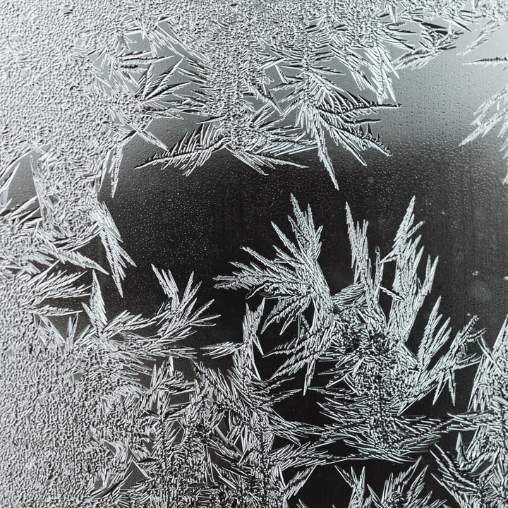 Eiskristalle an einer Glasscheibe signalisiert das der Naturstein von der Glaskaraffe die Kälte lange speichern kann.