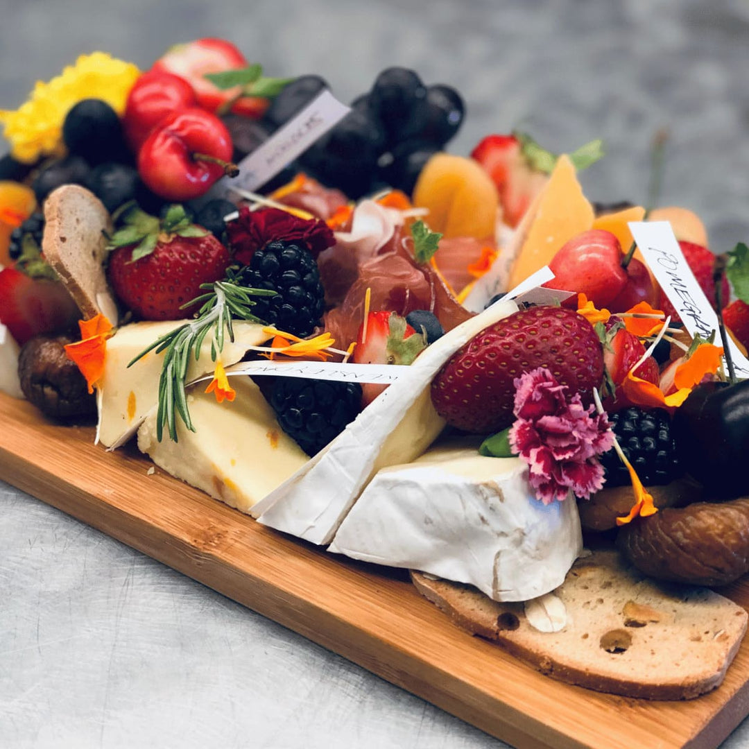 Servierbrett aus Altholz - Juvahem Lecker angerichtete Snacks, wieKäse und Beeren auf einem Holzbrett - schräge Draufsicht