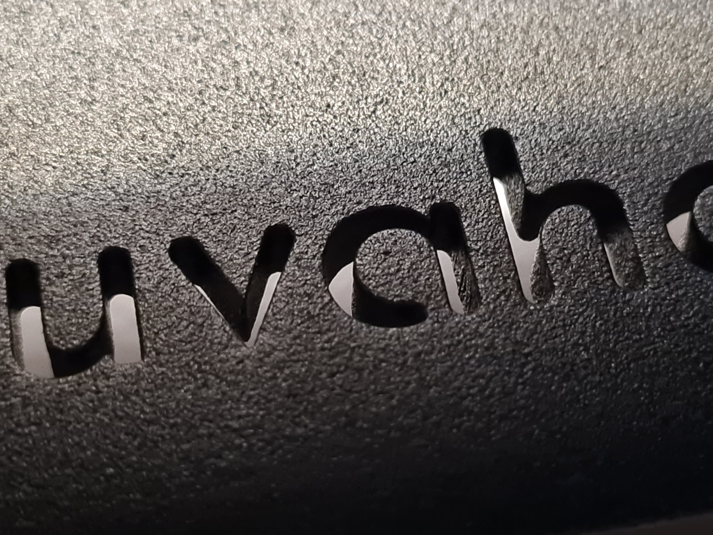 Detailaufnahme des durchgelaserten Logo Juvahem in den schwarzen pulverbeschichteten Stahlfuß der Etagere Hightray