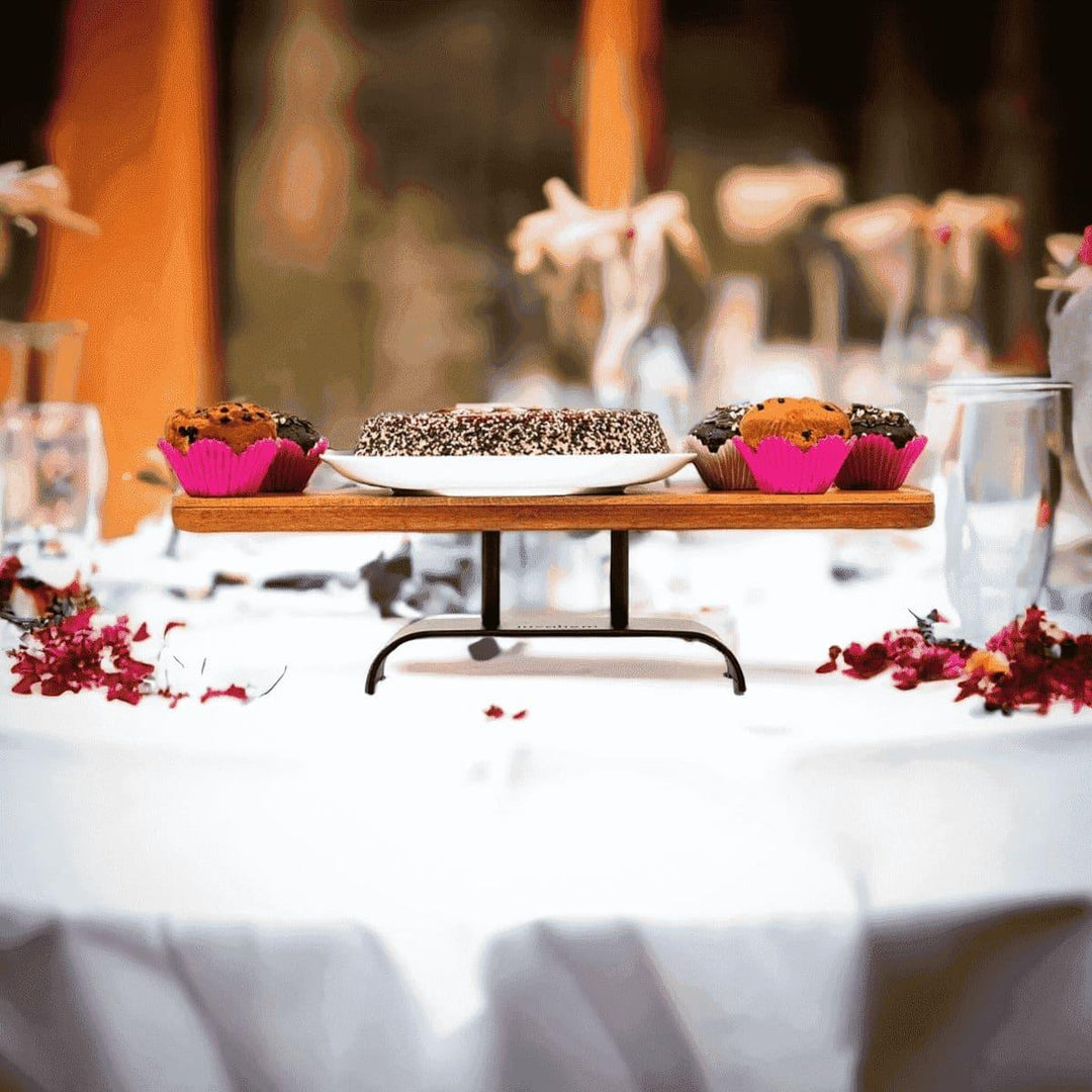Mit Kuchen und Muffins dekorierte längliche Etagere aus Eiche Altholz mit einem pulverbeschichtetem schwarzen Stahlfuß auf einem gedeckten Tisch einer Hochzeitsfeier