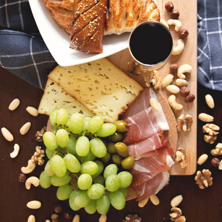 Frühstücksbrettchen aus Altholz - Juvahem Lecker angerichtete Snacks, wie Käse, Schinken, Nüsse und Weintrauben auf einem Holzbrettchen - Draufsicht