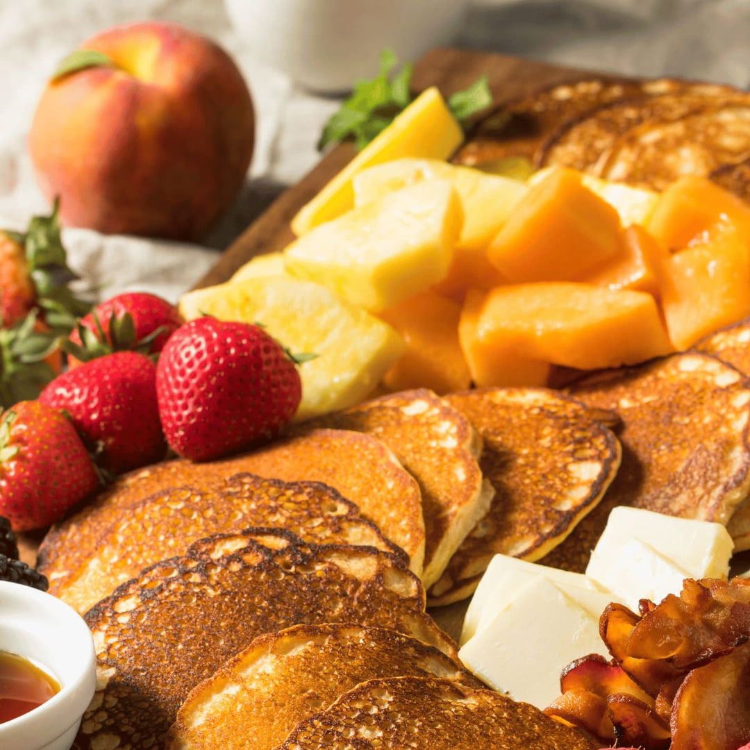 Servierbrett aus Altholz - Juvahem Lecker angerichtete Snacks, wie Pancakes, Obst und Erdbeeren auf einem Holzbrett - schräge Draufsicht