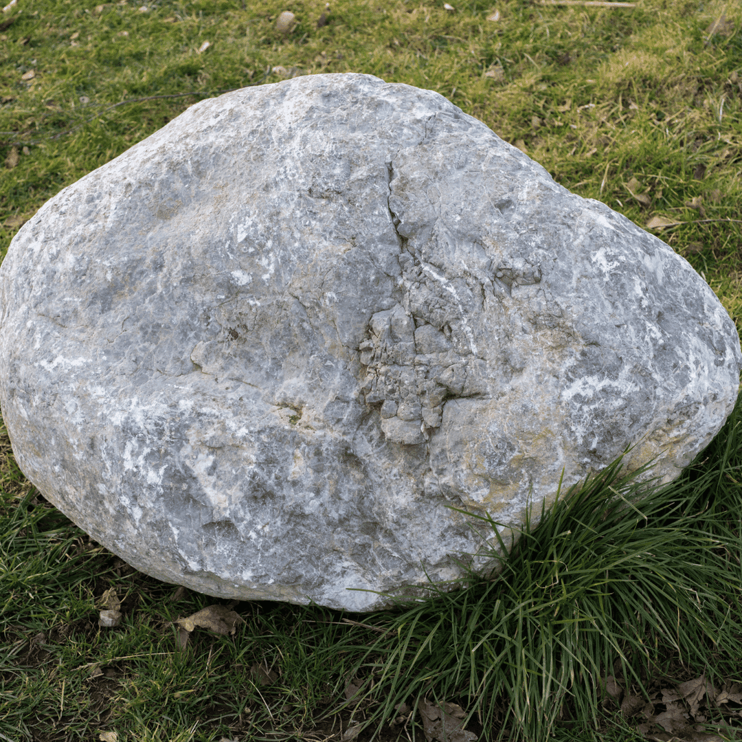 Ein riesig großer Naturstein aus Steatit liegt auf einer Rasenfläche. Der Naturstein aus den Produkten von Juvahem ist mehrere Milliarden Jahre alt.