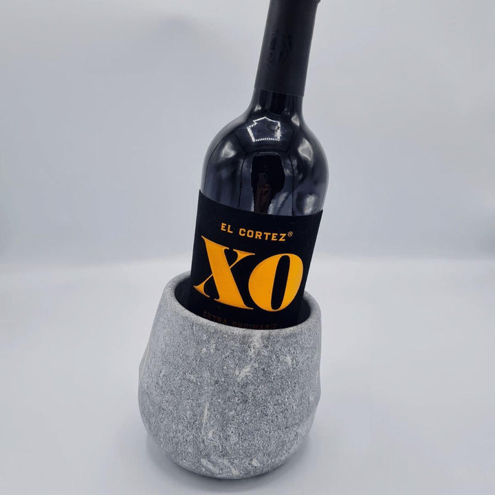 Ein grauer, rundlicher Weinkühler aus Naturstein, karelischer Steatit aus Skandinavien, in dem eine dunkle Weinflasche steht, da er die Kälte sehr lange hält.